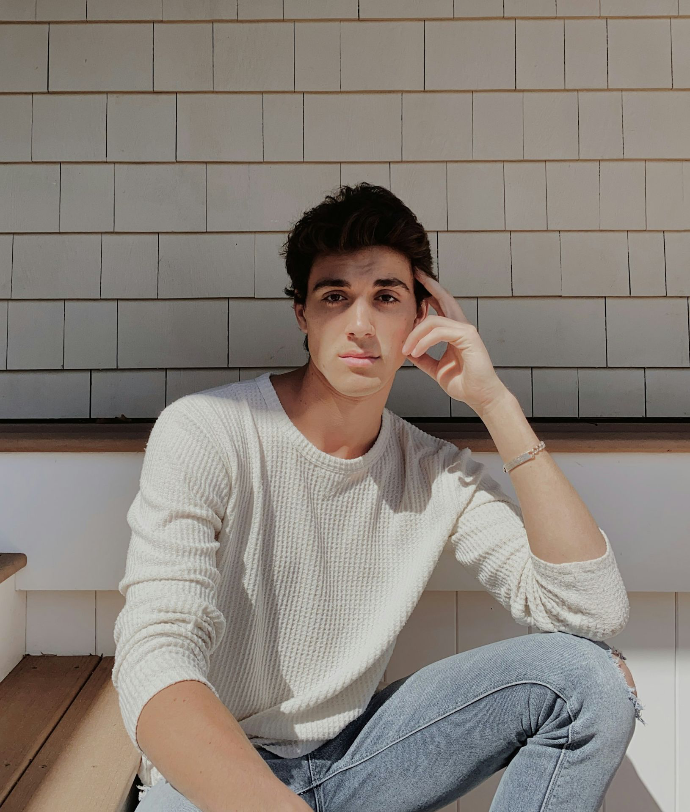 woman in white sweater and blue denim jeans sitting on white ceramic floor tiles